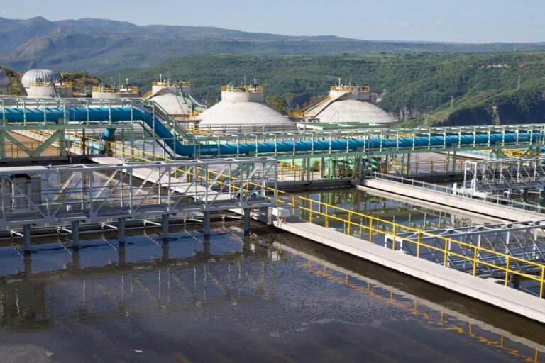 "Instalaciones industriales de tratamiento de agua con tuberías y tanques en un entorno montañoso.